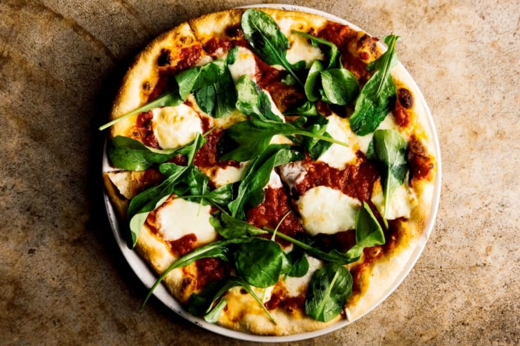 A pizza with mozzarella and fresh spinach