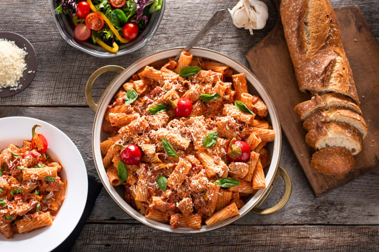 Rigatoni with tomato sauce next to a salad and bread