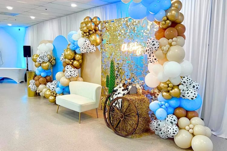 Décor setup with different colored balloons, hay, a couch and backdrops, at Room6Twelve