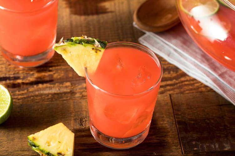 A glass of rum punch garnished with a pineapple wedge