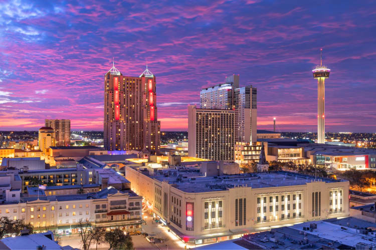 A city skyline at night under a purple sky