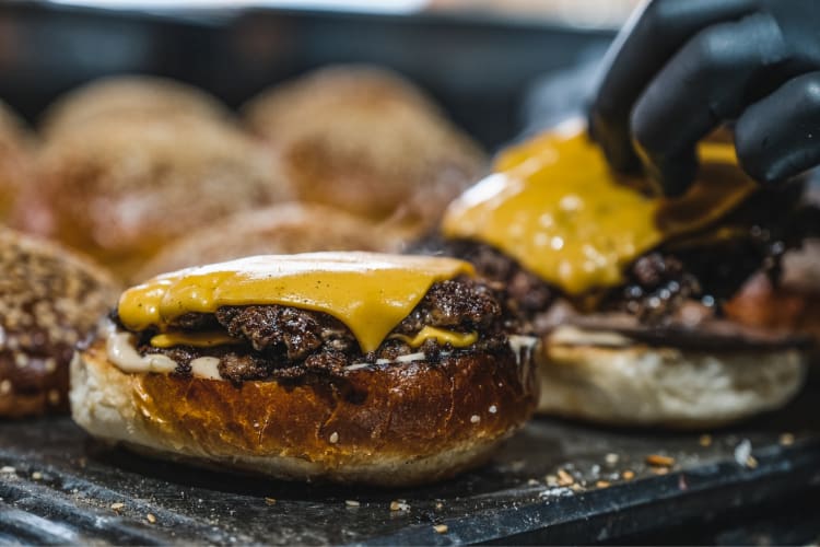 Cheese melting on burger patties on a grill