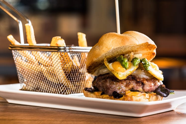 Burger with a variety of toppings on and fries on the side