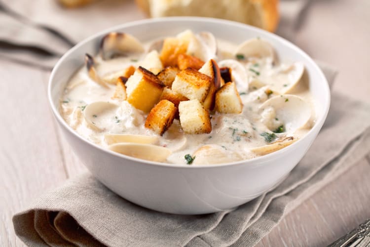 Seafood chowder in a white bowl with croutons on top