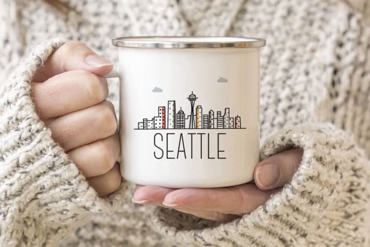 A person holding camping mug that says Seattle