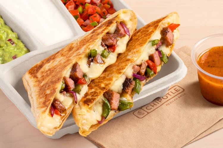 A quesadilla next to sauce and guacamole
