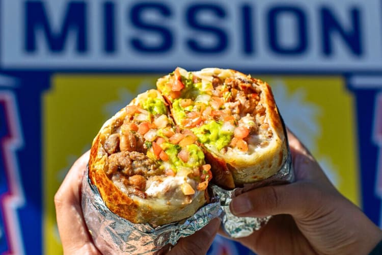 Close-up of two hands holding two halves of a burrito from Señor Sisig
