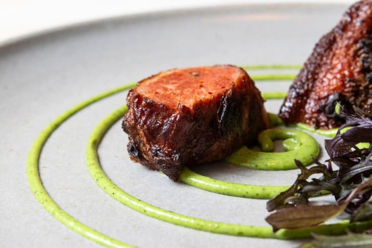 Close-up of a piece of steak plated with a green sauce from Sepia in Chicago