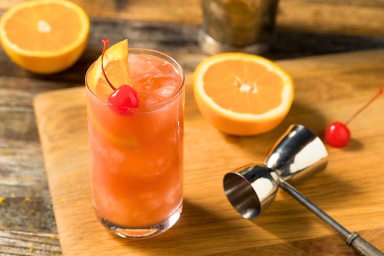 Sex on the beach, a vodka cocktail, on a wooden board with a shot pourer
