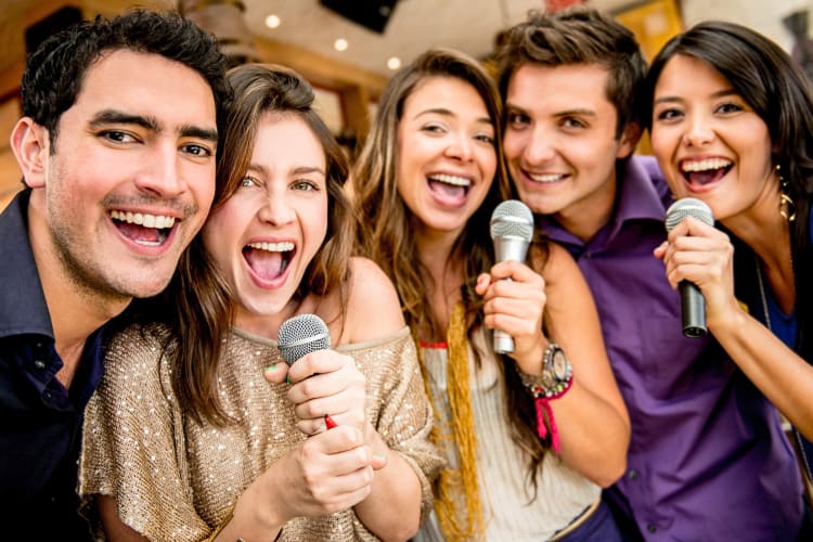 Close-up view of five friends singing karaoke together
