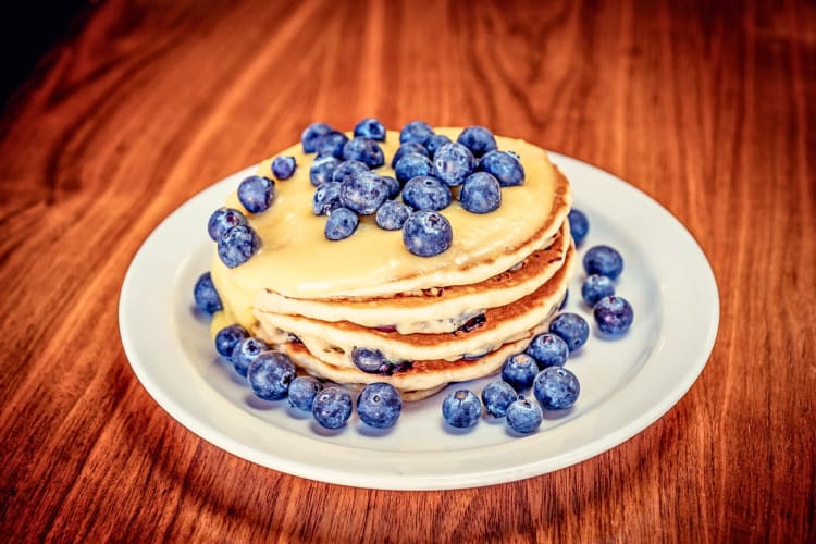 Stack of pancakes topped with syrup and blueberries, from Slappy Cakes