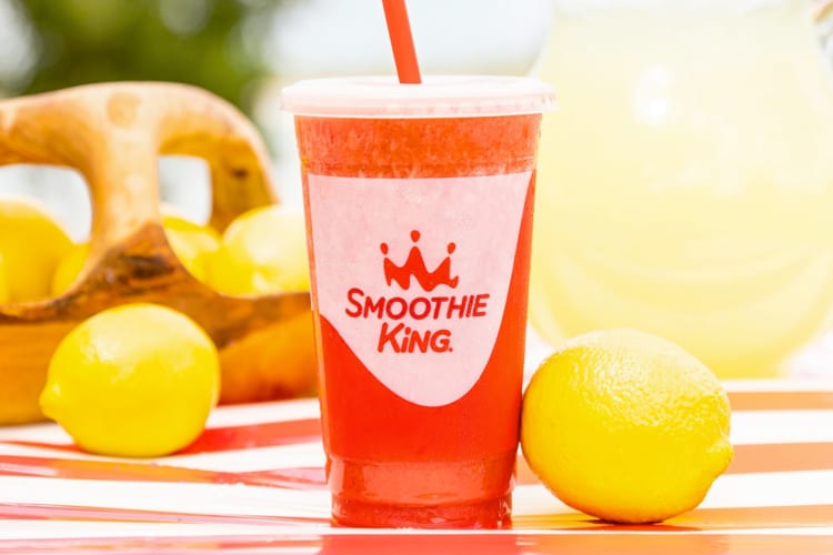 A strawberry lemonade drink next to fresh lemons
