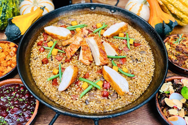 Paella surrounded by various side dishes, from Socarrat Paella Bar