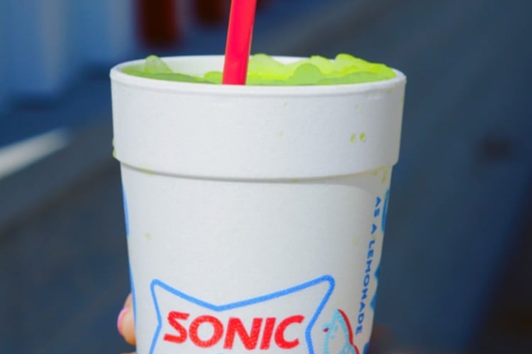 A person holding a Sonic cup with a green slushie