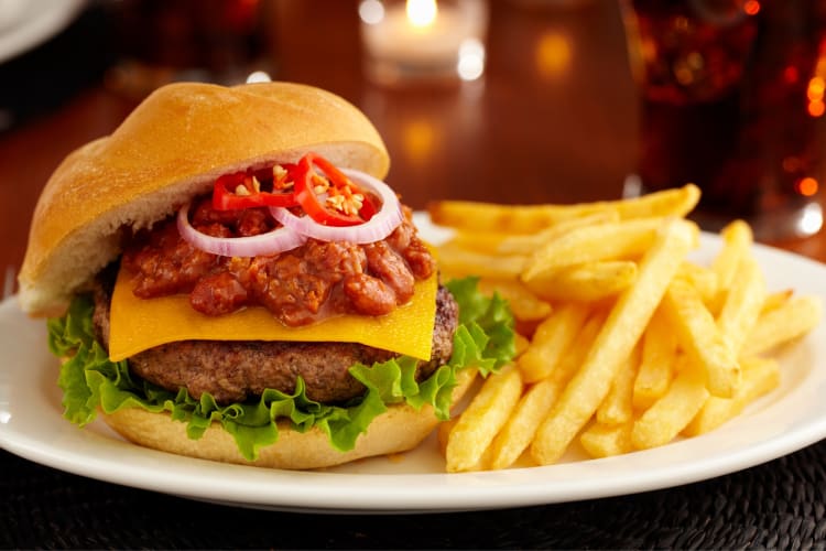 A chili cheeseburger next to fries