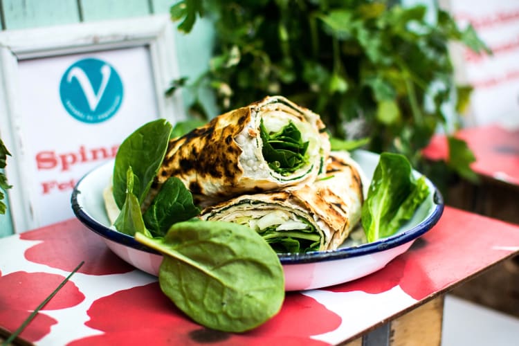 Spinach and feta wrap surrounded by extra spinach, in a bowl