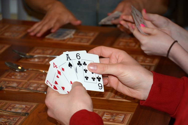 People's hands holding cards while playing a game called Spoons