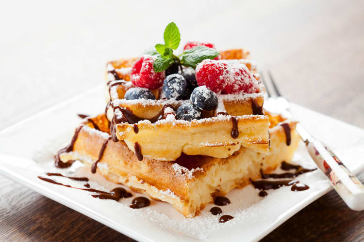 Waffles topped with blueberries, raspberries and chocolate sauce
