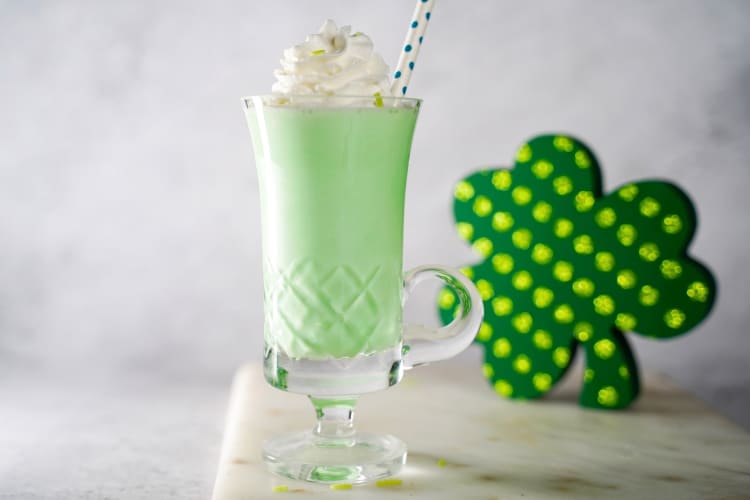 A green milkshake next to a four leaf clover decoration