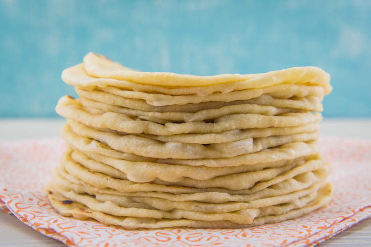 Stack of tortillas in front of a blue background