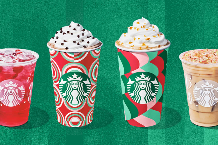 Four Starbucks drinks in festive cups next to caramels, mint candies and sugar cookies