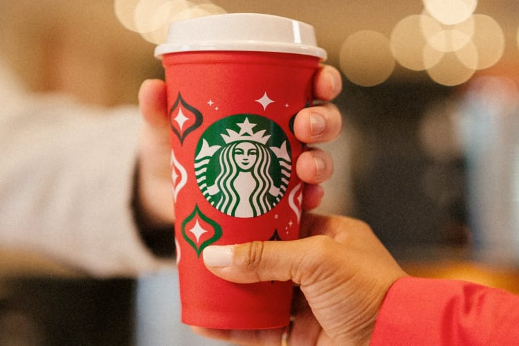 A person handing another person a red Starbucks cup
