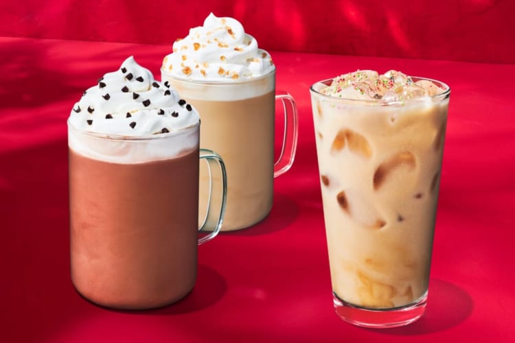 Two hot drinks with whipped cream and an iced coffee from Starbucks