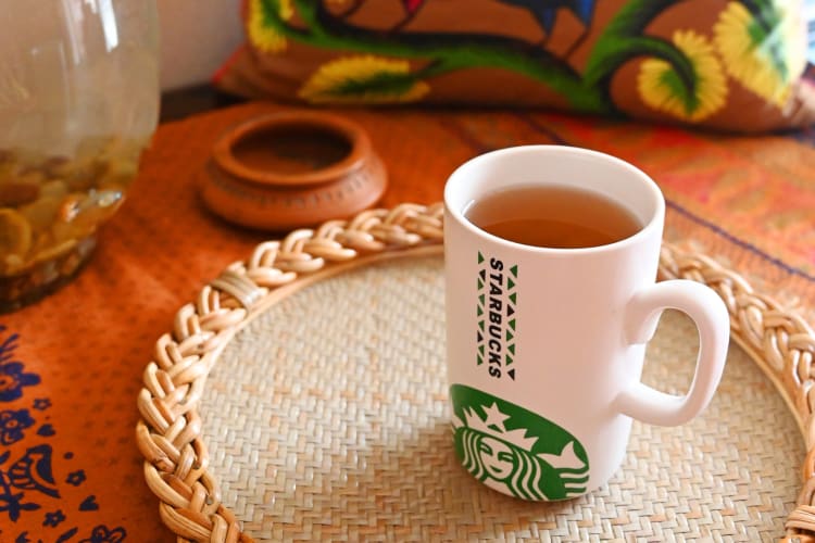 A Starbucks mug with tea on a table