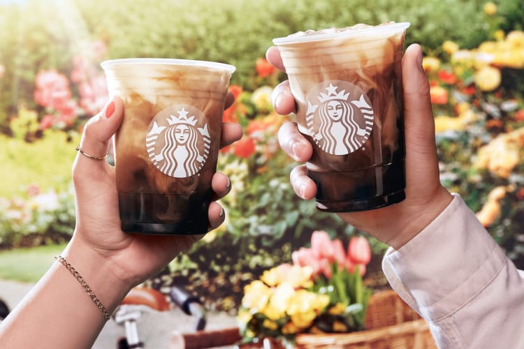 Two people holding iced coffee from Starbucks