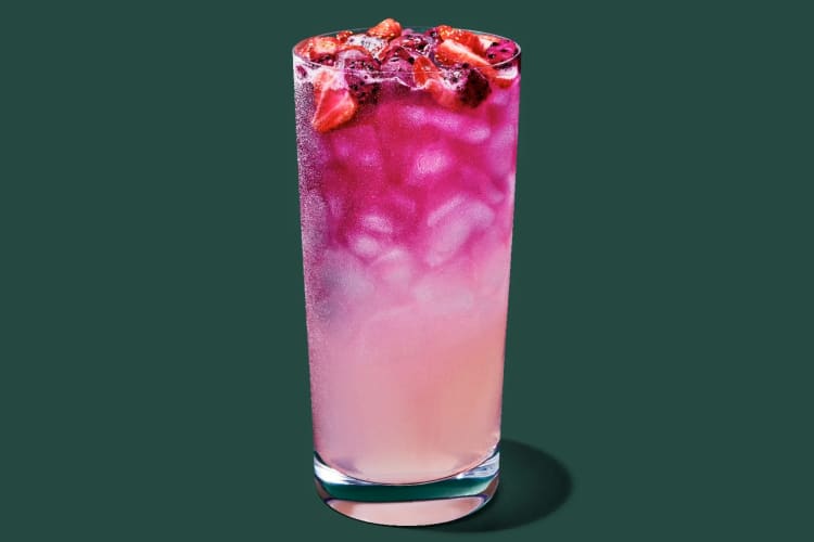 A pink drink topped with strawberries and dragonfruit