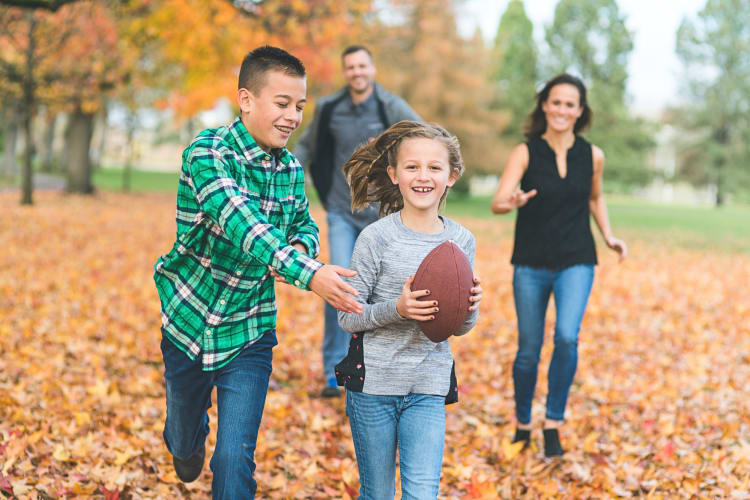 Family of four playing football, two kids in the front with the parents following behind