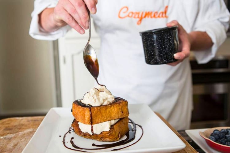 A chef drizzling chocolate sauce on a French toast dish