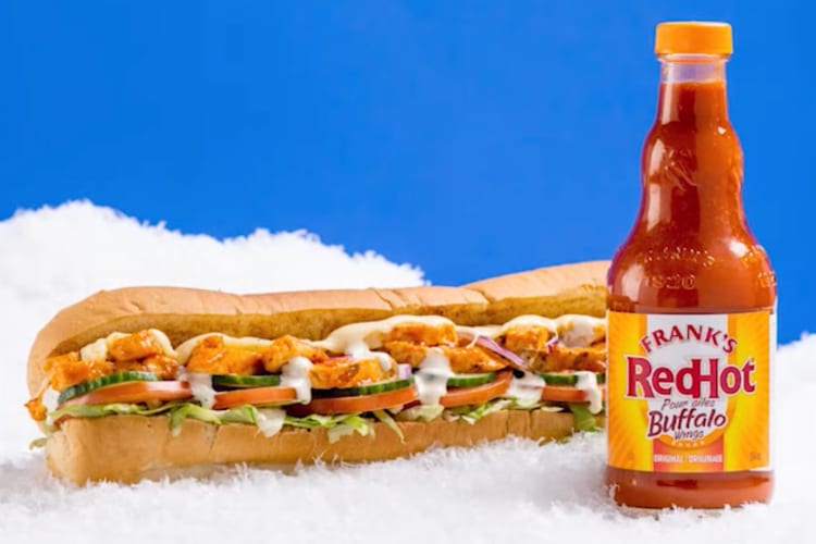 A bottle of Frank's RedHot Buffalo sauce next to a Subway sandwich