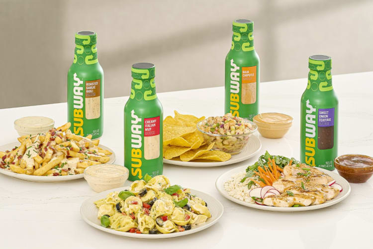 Green bottles of Subway sauce next to various dishes