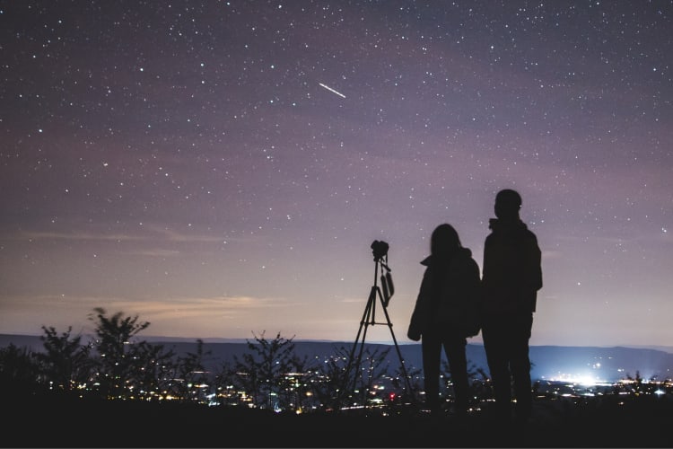 The silhouettes of two people stargazing