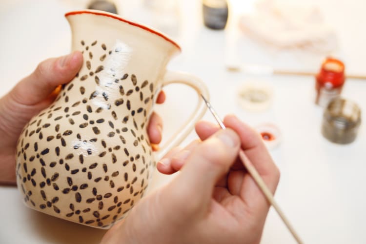 A person painting a small jug