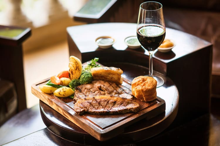 Sunday roast served on a wooden board next to a glass of wine