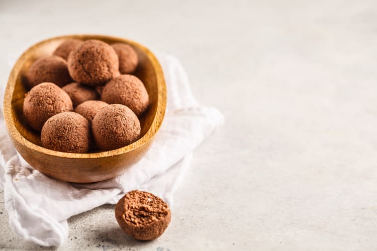 Sunnundalu balls in a bowl with a half eaten one sitting outside the bowl