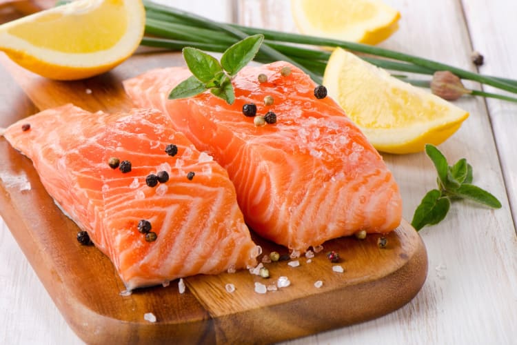 Raw salmon fillets seasoned with salt, peppercorn and lemon