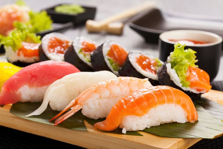 Variety of sushi, including Nigiri, with sauce in the background