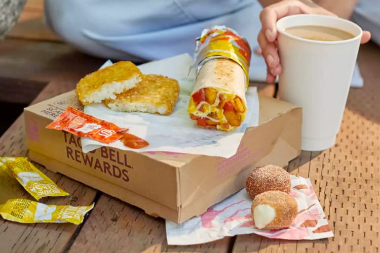 A Taco Bell breakfast burrito next to hash browns and donuts