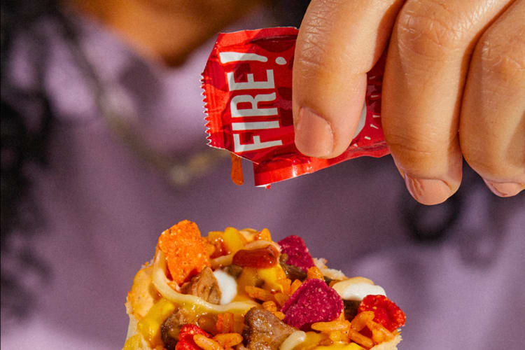 A person putting hot Taco Bell sauce on a burrito