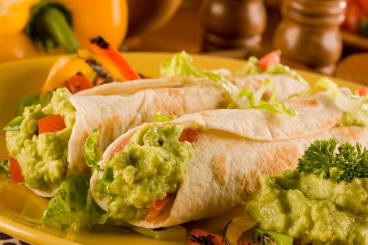 A couple of burritos filled with guacamole