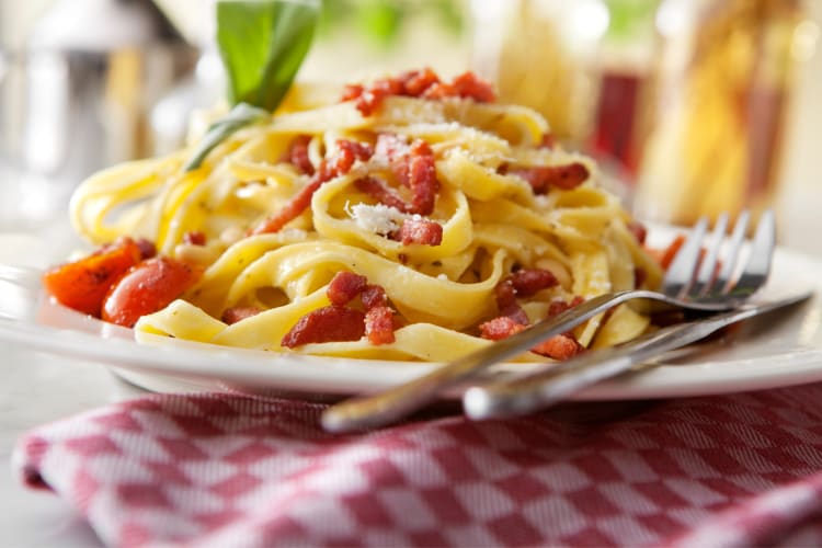 Tagliatelle Carbonara on a plate with a knife and fork beside it