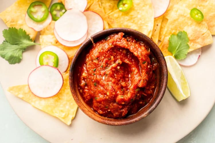 A bowl of salsa next to tortilla chips