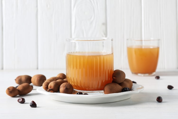 Tamarind pods and tamarind juice in a glass