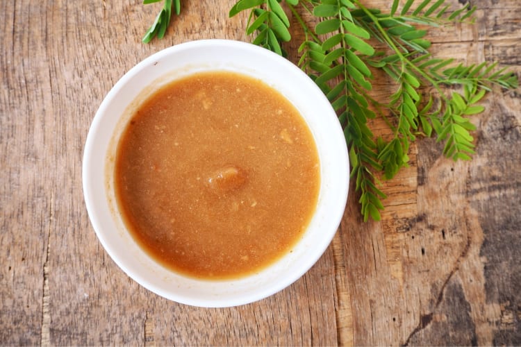 A bowl of tamarind sauce on a wooden surface