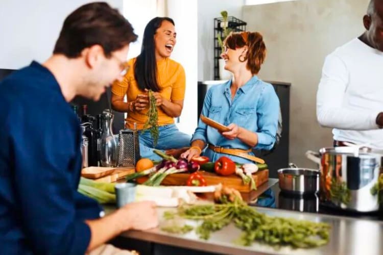 three people laughing and chopping vegetables together as a team building activity in Houston