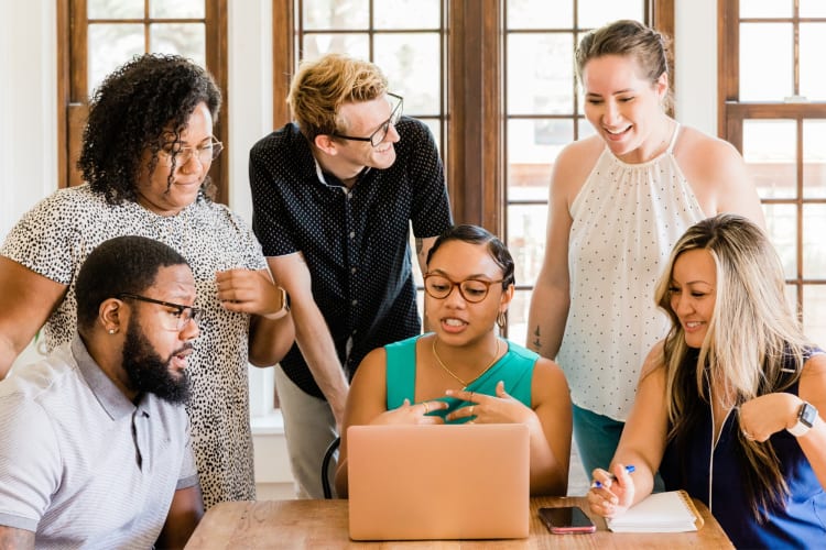 Co-workers chatting around a laptop