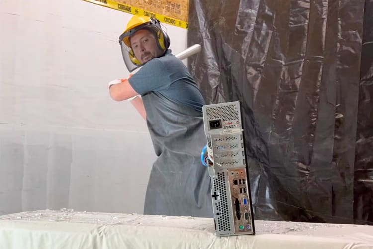 A person in a rage room smashing a computer monitor